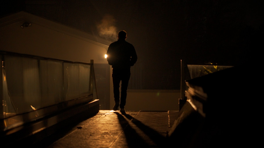 A figure walking through warm light at night